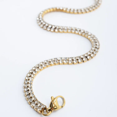 Gold bracelet with clear gemstones on a white background