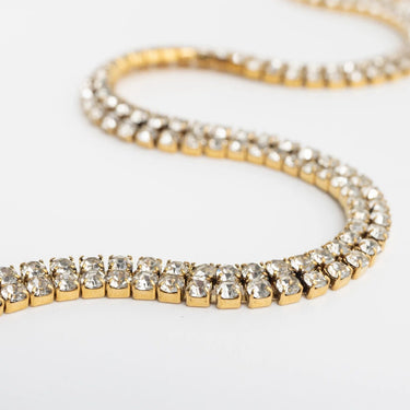 Gold bracelet with clear gemstones on a light gray background