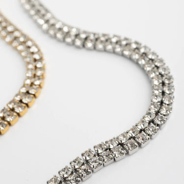 Close-up of a silver and gold bracelet with clear gemstones on a light gray background