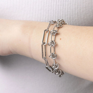 Silver chain bracelet on a wrist against a neutral background