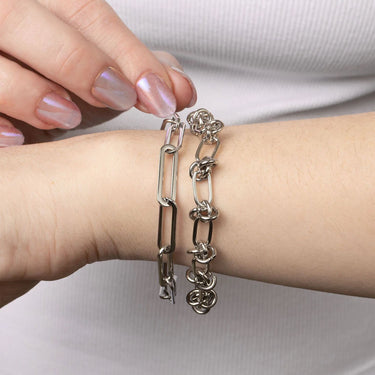Two silver bracelets on a wrist with a neutral background