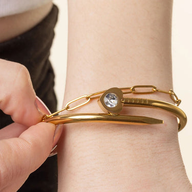 Gold bracelet with a heart-shaped clasp worn on a wrist