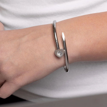 Silver bracelet with a heart-shaped gemstone on a wrist against a white background