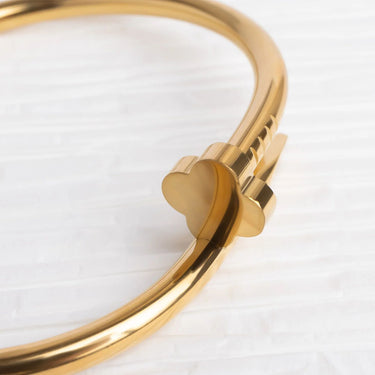 Gold bracelet with a heart-shaped clasp on a white background