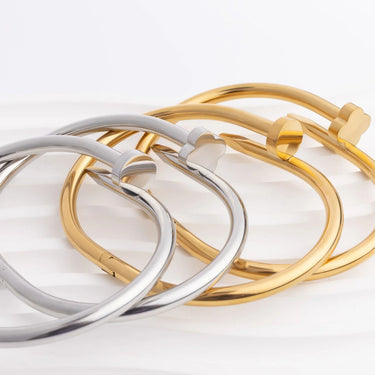 Three bangles in gold, silver, and rose gold on a light background