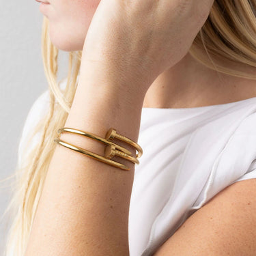 Gold bracelet on a person's wrist with a neutral background