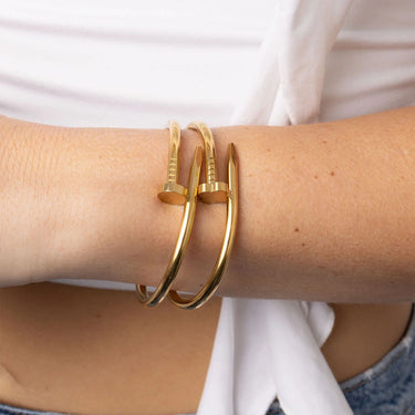 Gold bangles on a person's wrist with a white background