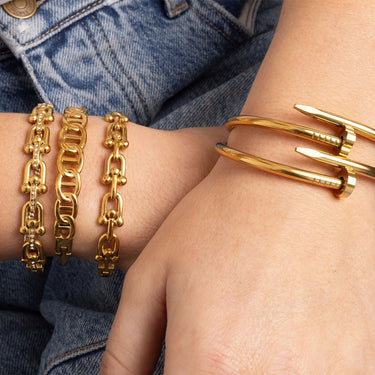 Gold bracelets on a person's wrist with denim background