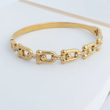 Gold chain bracelet on a light gray background