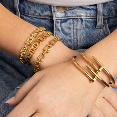 Gold bracelets on a person's wrist with a denim background