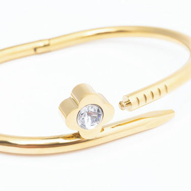 Gold bangle with a clear gemstone on a white background