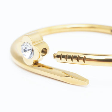 Gold bangle with a clear gemstone on a white background