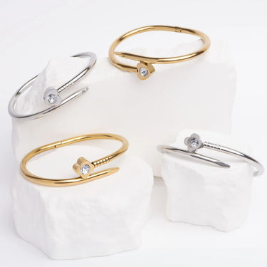 Set of gold and silver bangle bracelets with clear stones on a white background
