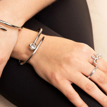 Close-up of a hand wearing silver rings and bracelets on a black background
