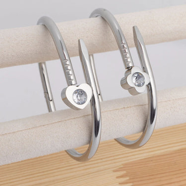 Silver hoop earrings with gemstones on a wooden surface