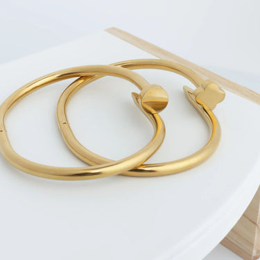 Two gold bangles on a white surface