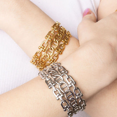Gold and silver chain bracelets on a wrist against a white background
