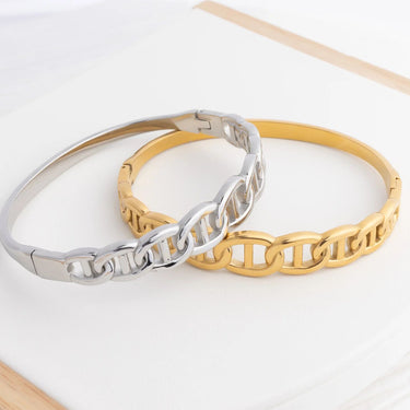 Two bracelets, one silver and one gold, on a light background