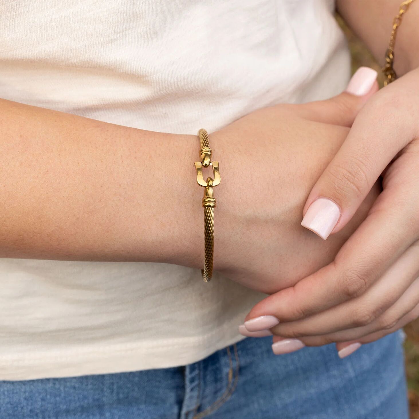 Gold bracelet with buckle clasp on a wrist with a blurred background