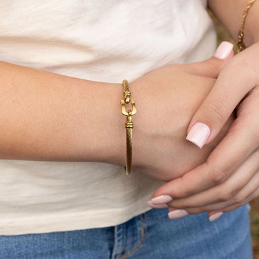 Gold bracelet with buckle clasp on a wrist with a blurred background