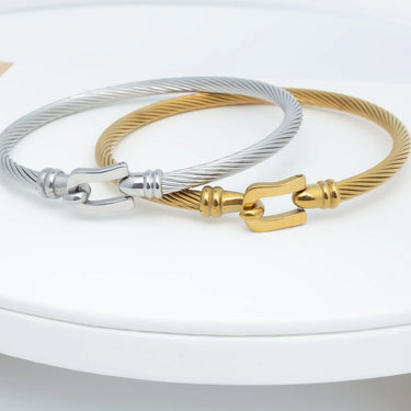 Two bracelets, one silver and one gold, on a white surface.