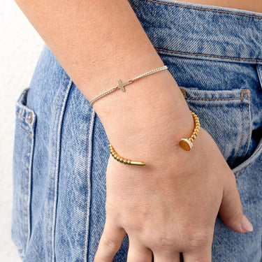 Gold bracelet on a wrist with a denim background