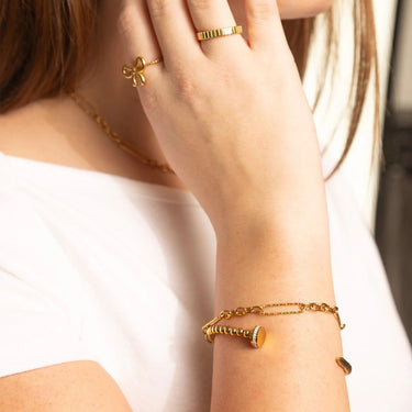 Close-up of a person wearing gold jewelry including a bracelet, ring, and necklace.