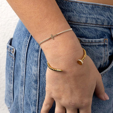 Gold bracelets on a wrist with a denim background