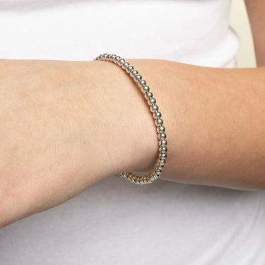 Silver beaded bracelet on a wrist against a white background