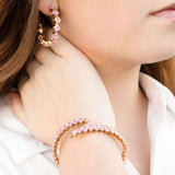 Close-up of a person wearing pink beaded hoop earrings and bracelet.