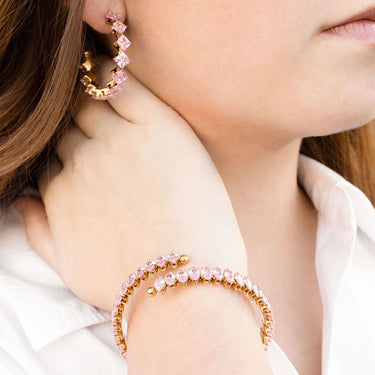 Close-up of a person wearing pink beaded hoop earrings and bracelet.