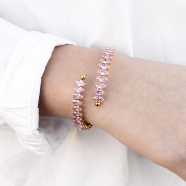 Pink beaded bracelet with gold accents on a wrist against a white background