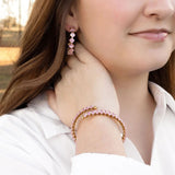 Close-up of a woman wearing pink beaded earrings and bracelet.