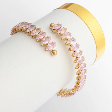 Gold bracelet with pink stones on a white surface