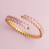Gold bracelet with pink gemstones on a pink background