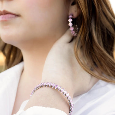 Close-up of a person wearing pink beaded earrings and bracelet.