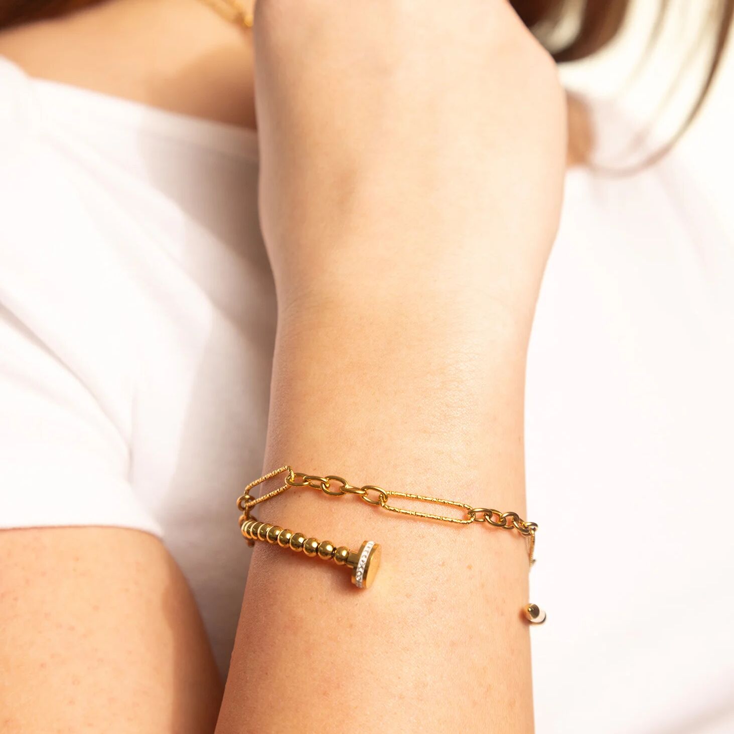 Gold bracelet on a person's wrist with a plain background
