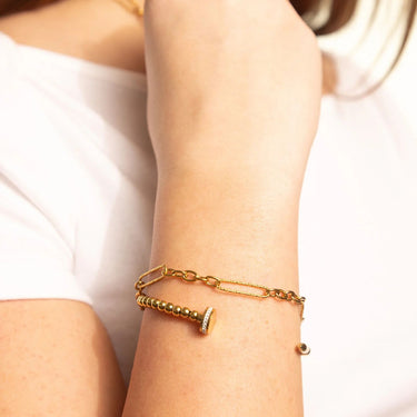 Gold bracelet on a person's wrist with a plain background