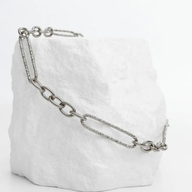 White textured bag with a silver chain detail on a white background