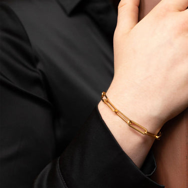 Gold bracelet on a person's wrist with a black shirt background