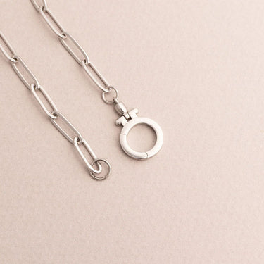 Silver necklace with a unique clasp on a light pink background