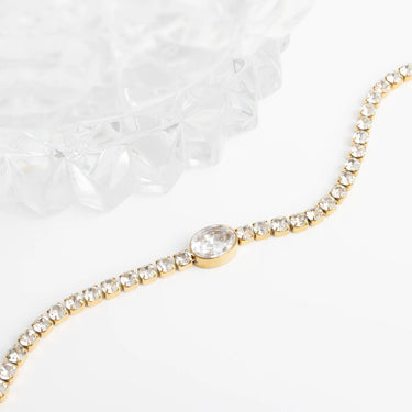 Gold bracelet with a central gemstone on a white background