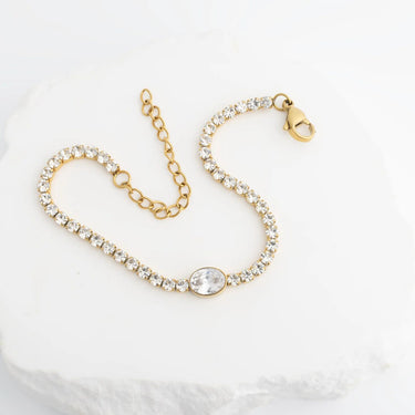 Gold bracelet with clear gemstones on a white background