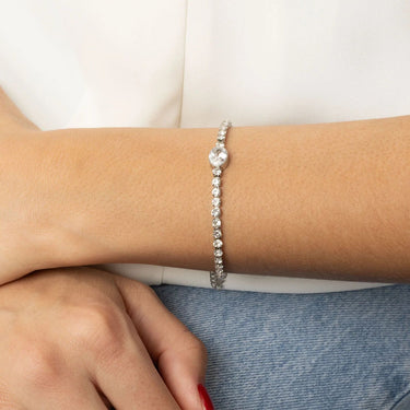 Silver bracelet on a wrist with a plain background