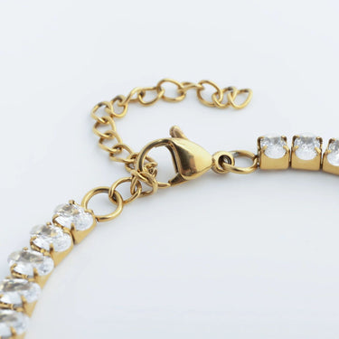 Gold bracelet with clear gemstones on a white background