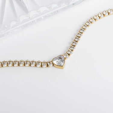 Gold bracelet with a heart-shaped clasp on a white background