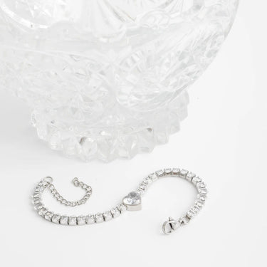 Silver bracelet with heart charm on a white background