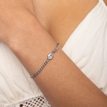 Silver bracelet with a clear gemstone on a person's wrist against a white background