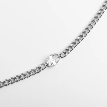 Silver chain bracelet with a clear gemstone on a light gray background