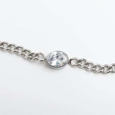 Silver chain bracelet with a clear gemstone on a white background